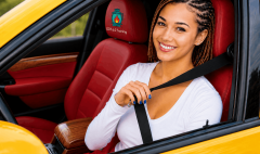 Woman wearing a seat belt while driving a car for road safety
