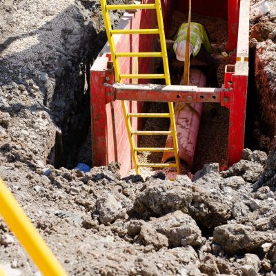 Groundworker,Installing,Clay,Drainage,Pipe,While,In,The,Trench,Supported