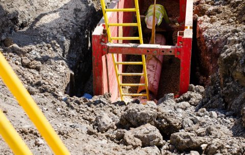 Groundworker,Installing,Clay,Drainage,Pipe,While,In,The,Trench,Supported