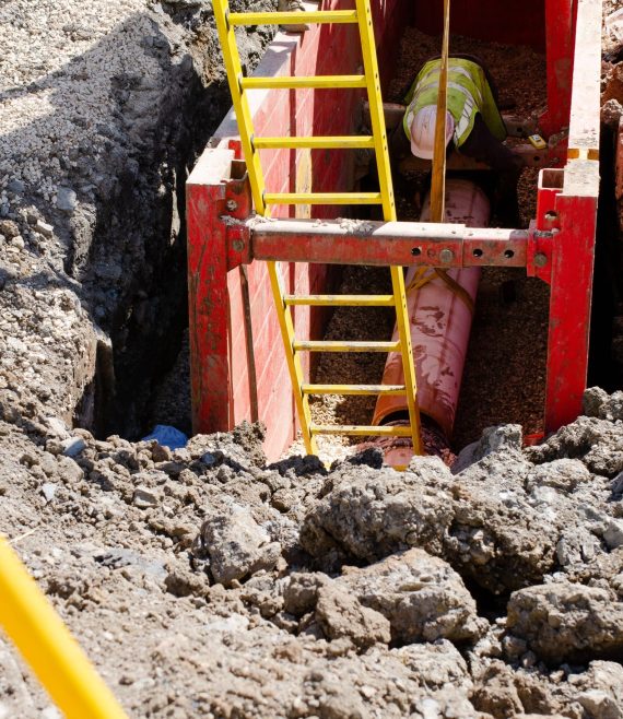 Groundworker,Installing,Clay,Drainage,Pipe,While,In,The,Trench,Supported